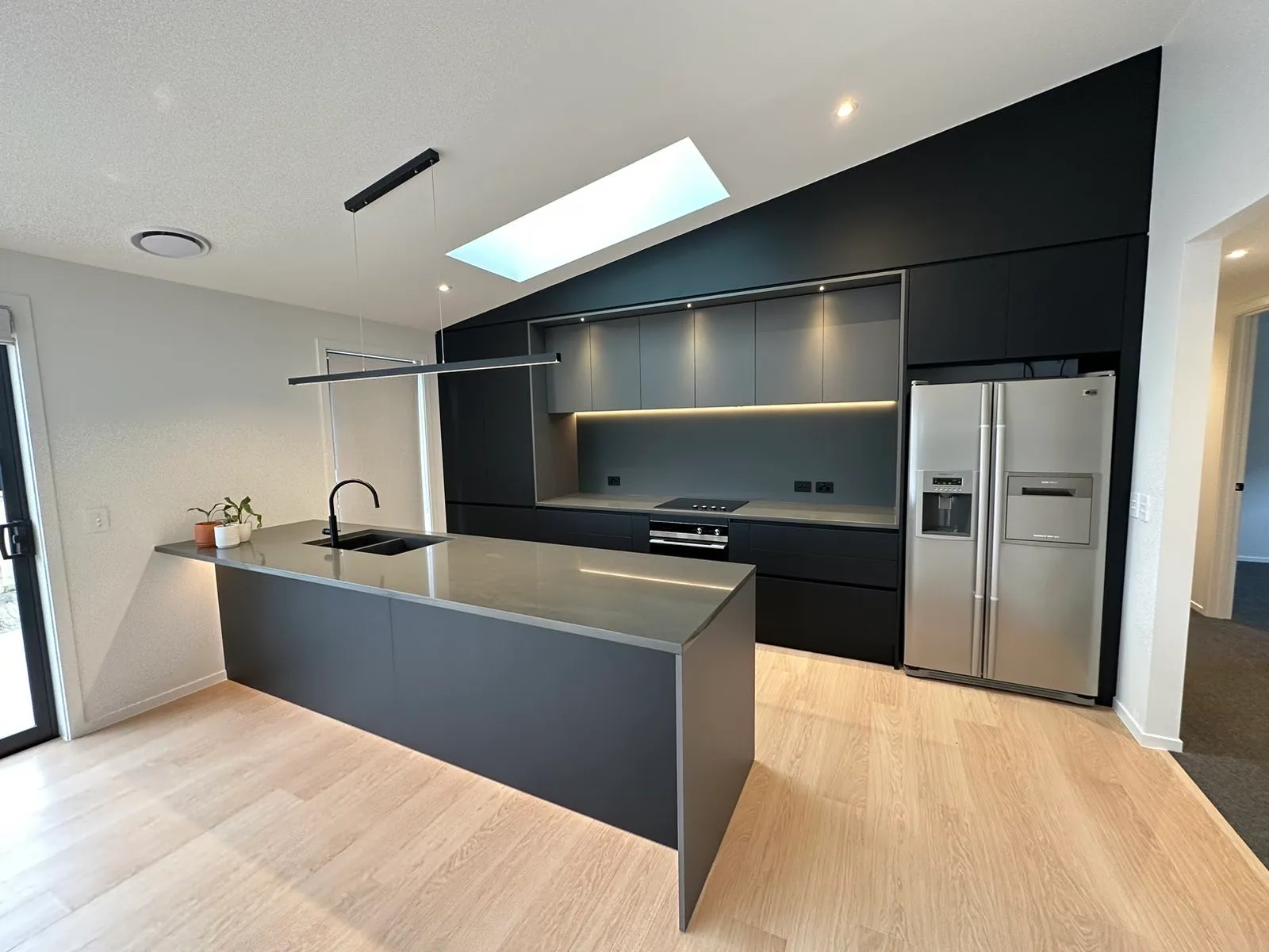Charcoal island in front of a full-height charcoal wall of cabinets