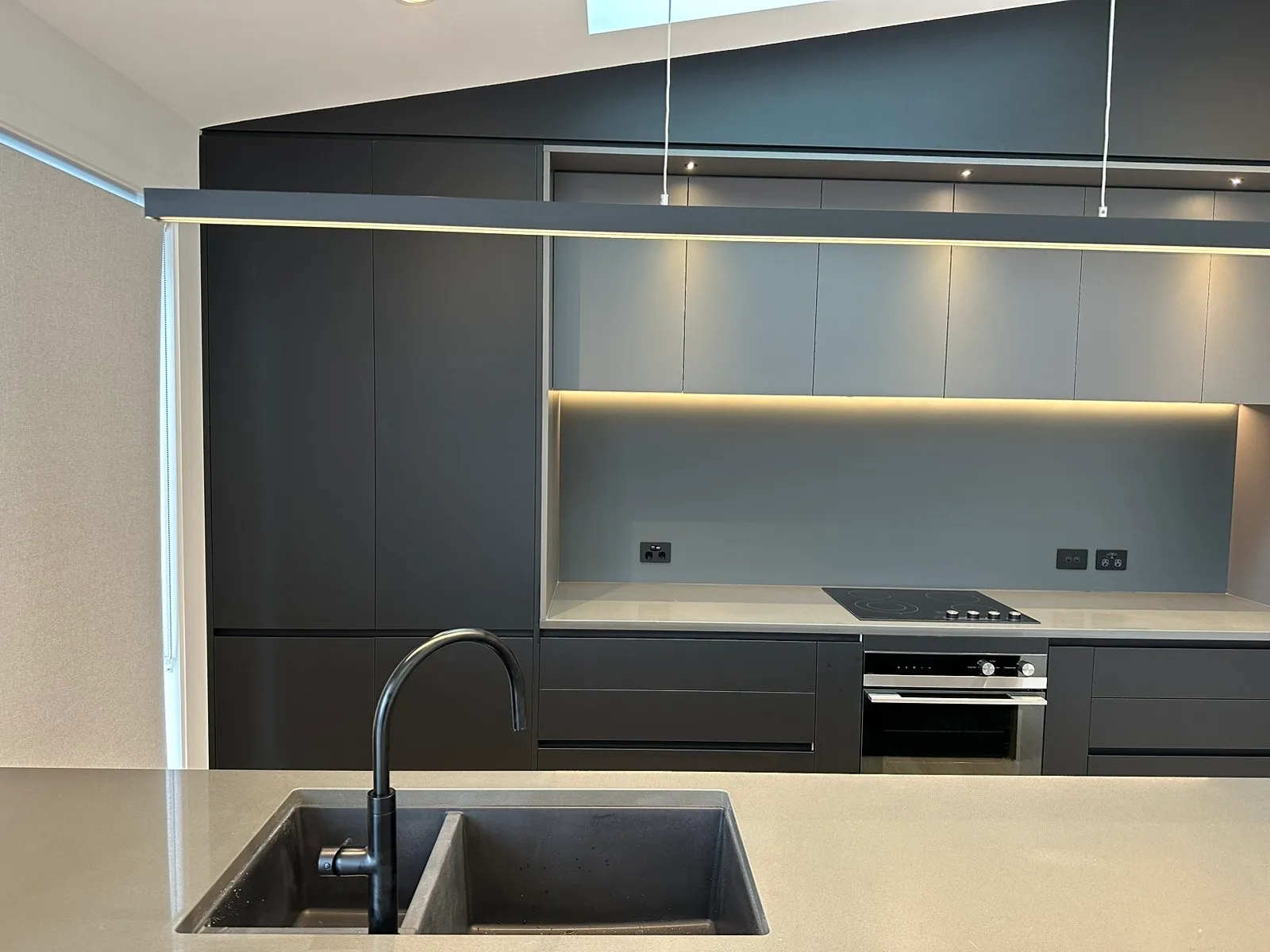 View over the island sink to the lit charcoal and grey back wall