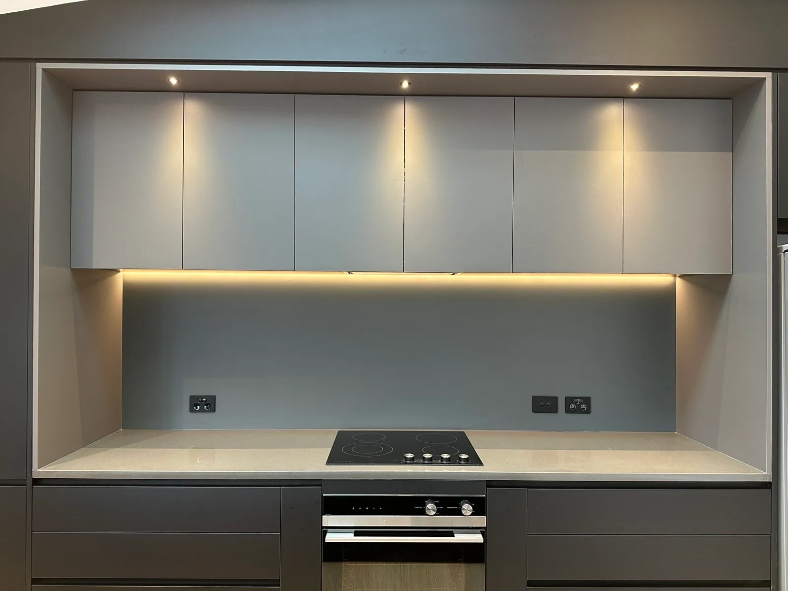 Grey overheads with LED strip lighting framed in charcoal cabinetry