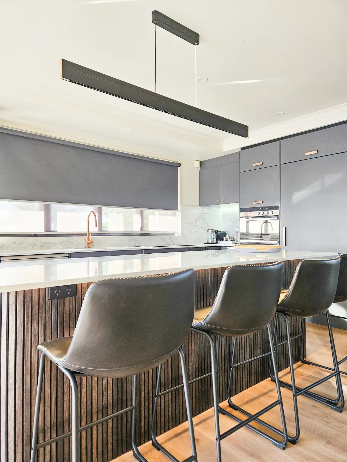 Portrait view along the fluted island and bar stools