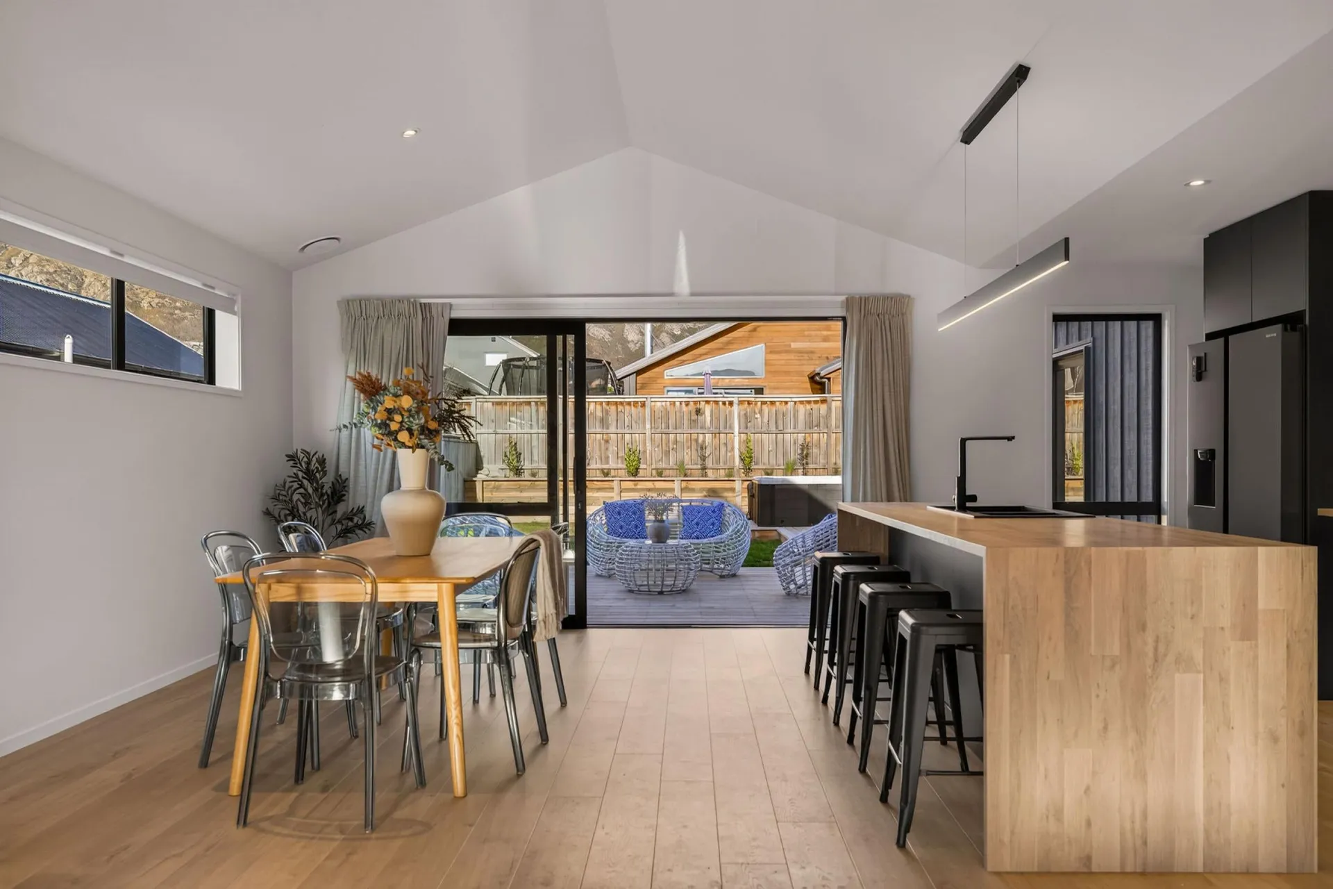 Timber-look waterfall island end with bar stools beside the dining area