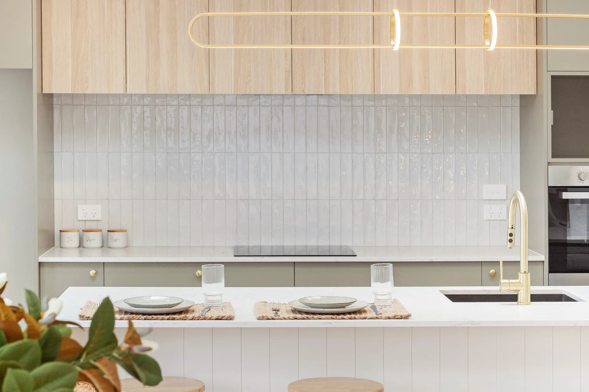 Tiled splashback below timber-look overheads behind a white panelled island