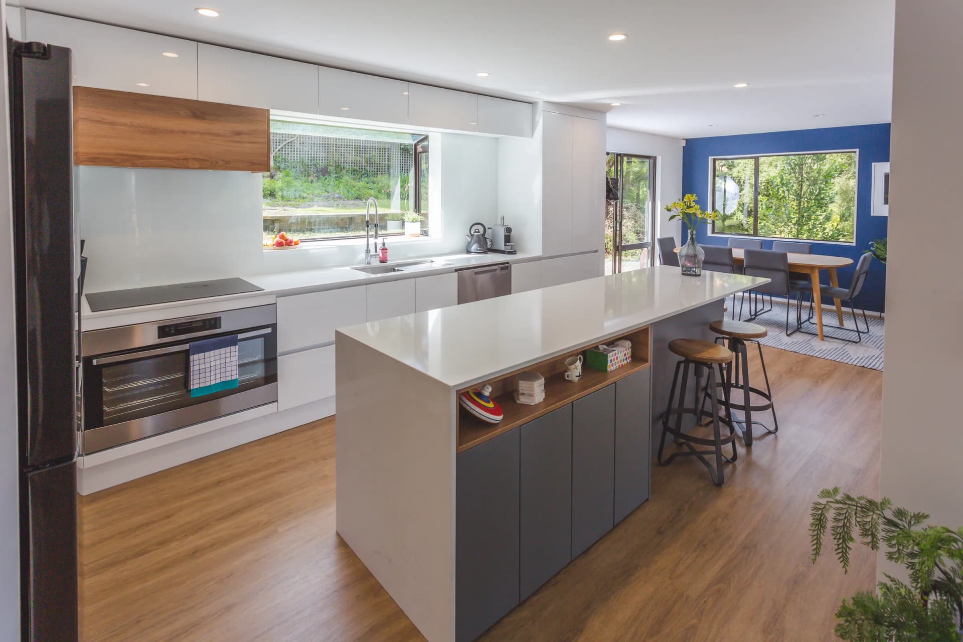 White handleless kitchen with a grey island and a timber-look box over the cooktop