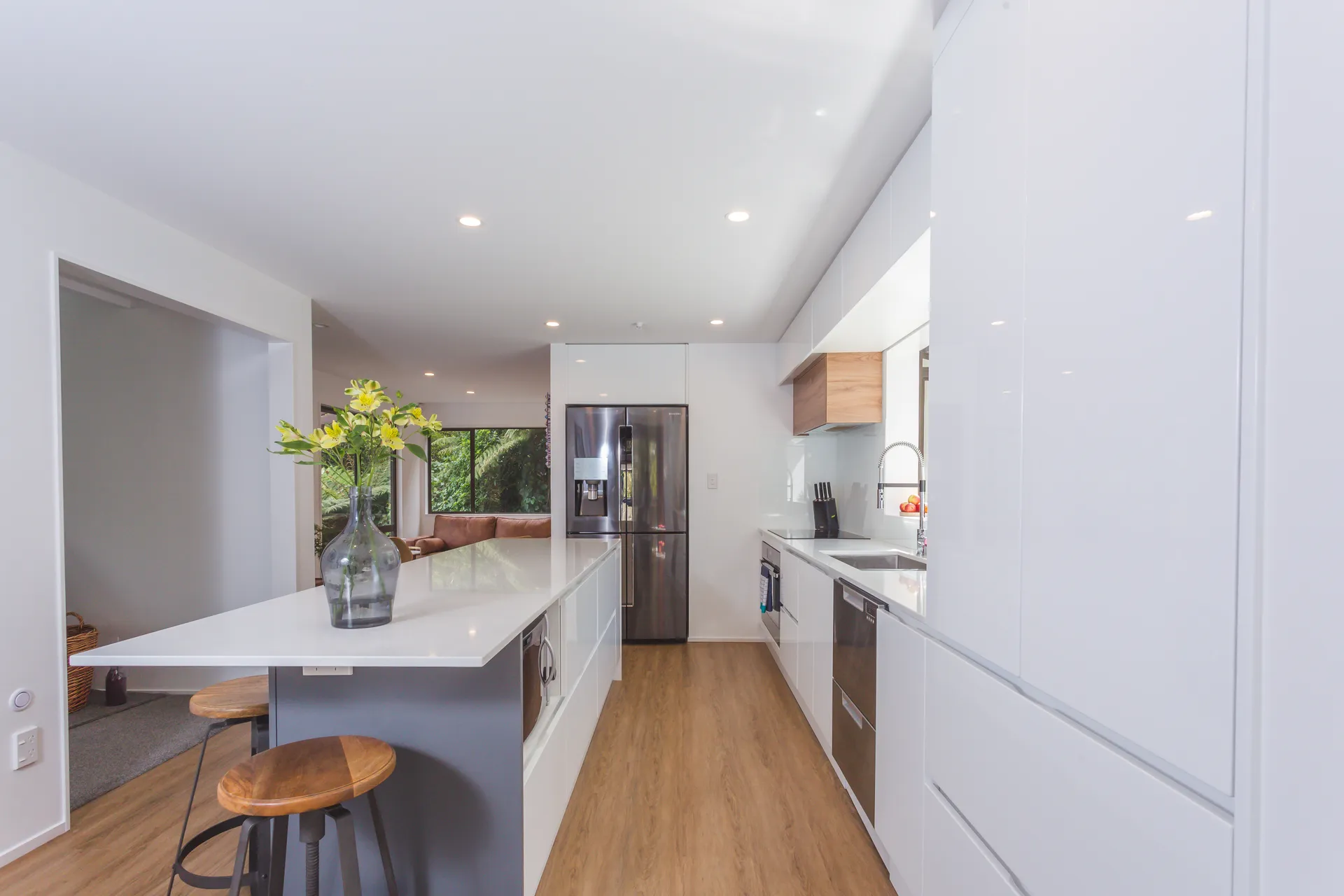 Galley past a grey island with stools to a white gloss run