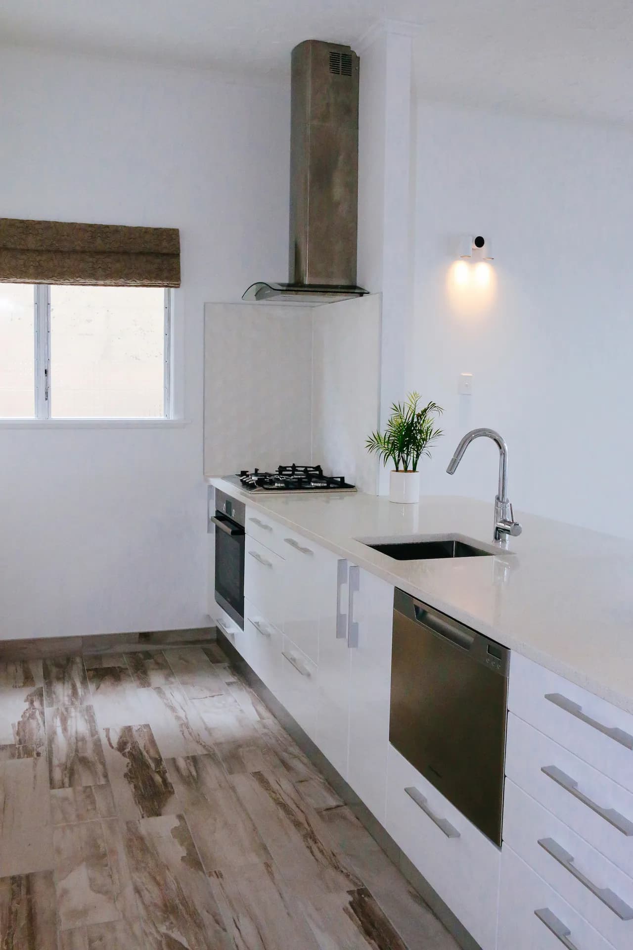 Portrait run of white gloss cabinets with bar handles and a rangehood