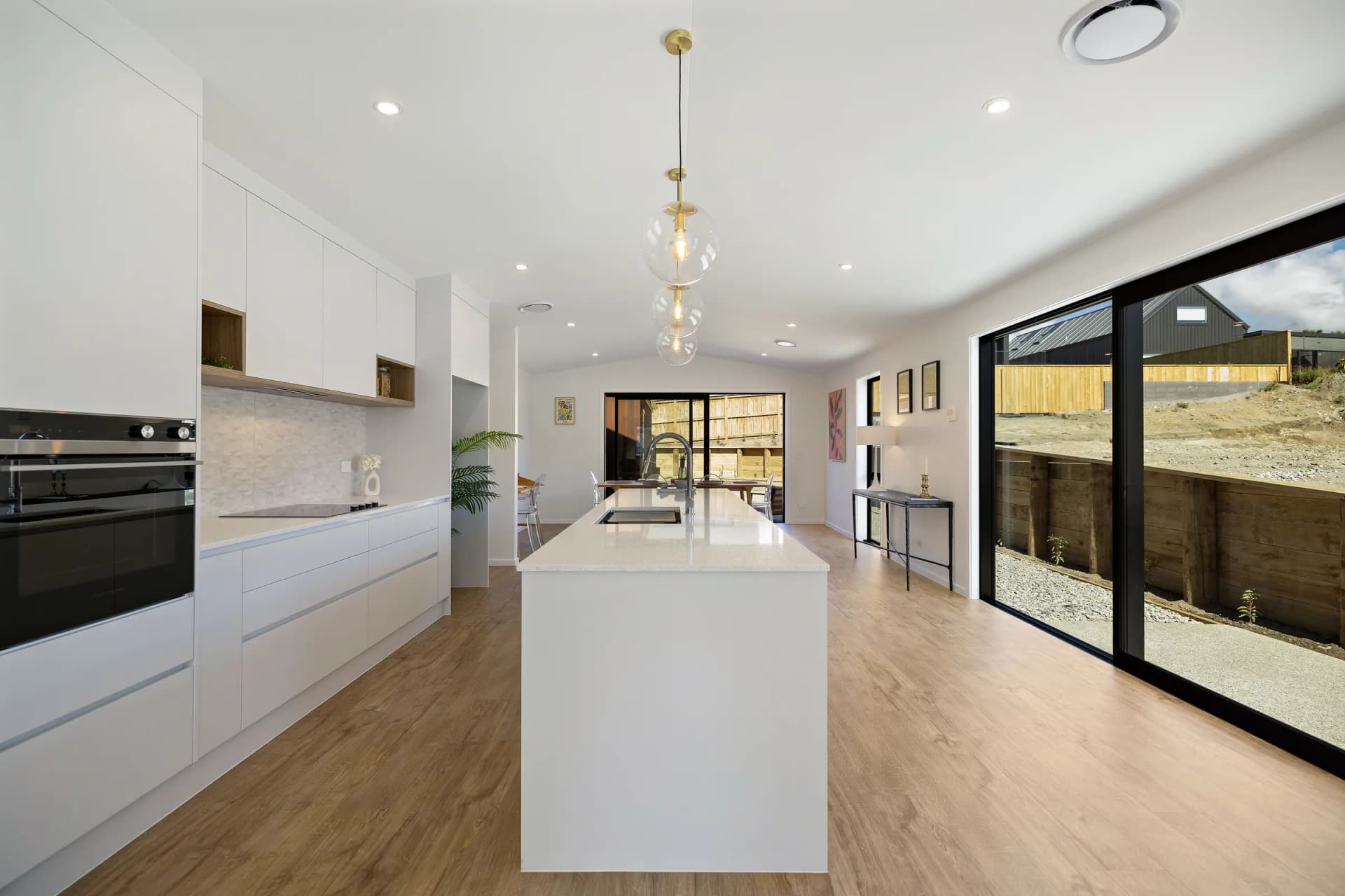 Long white island and handleless run of cabinets toward sliding doors