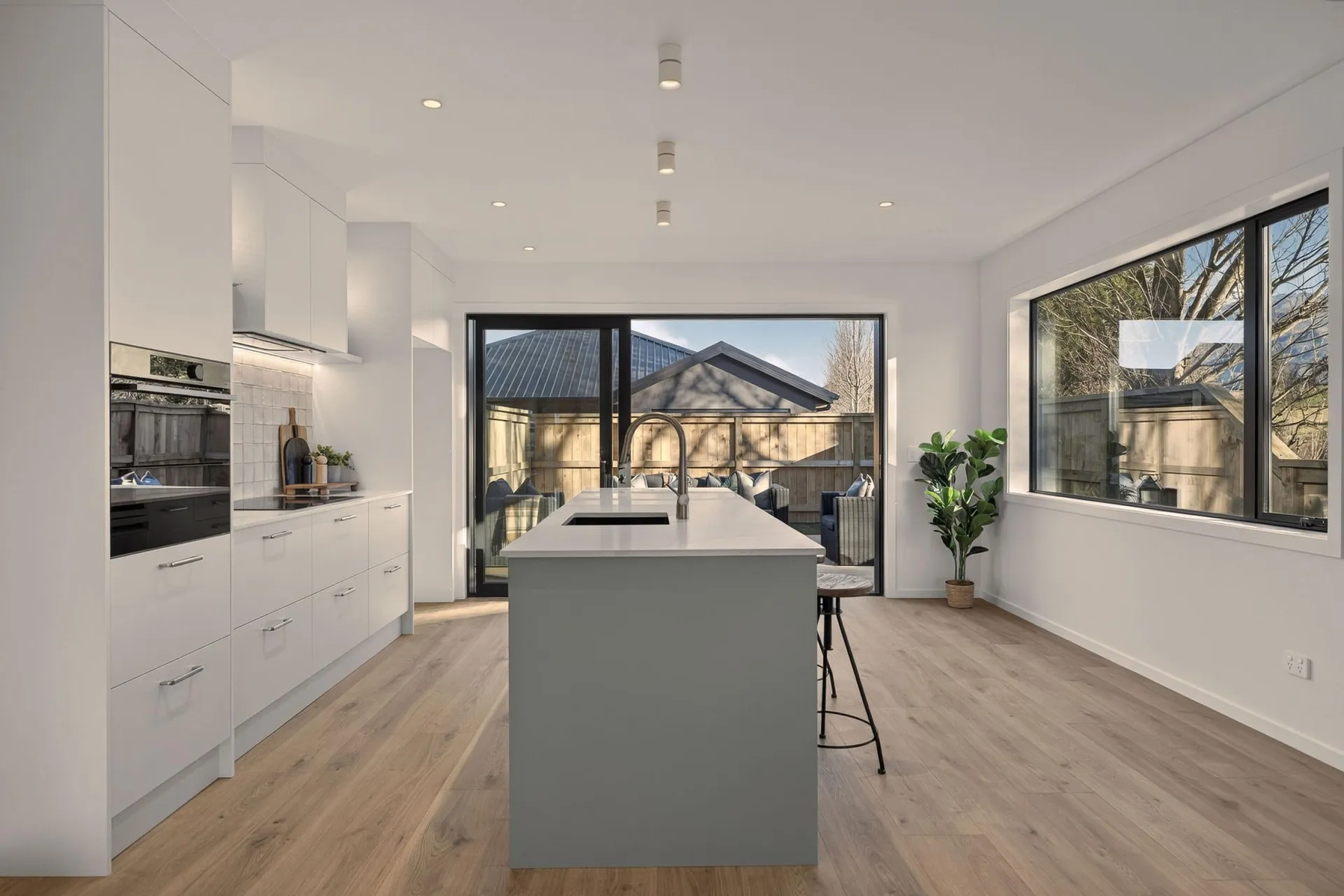 Grey-green island in line with a white run of cabinets and wall ovens