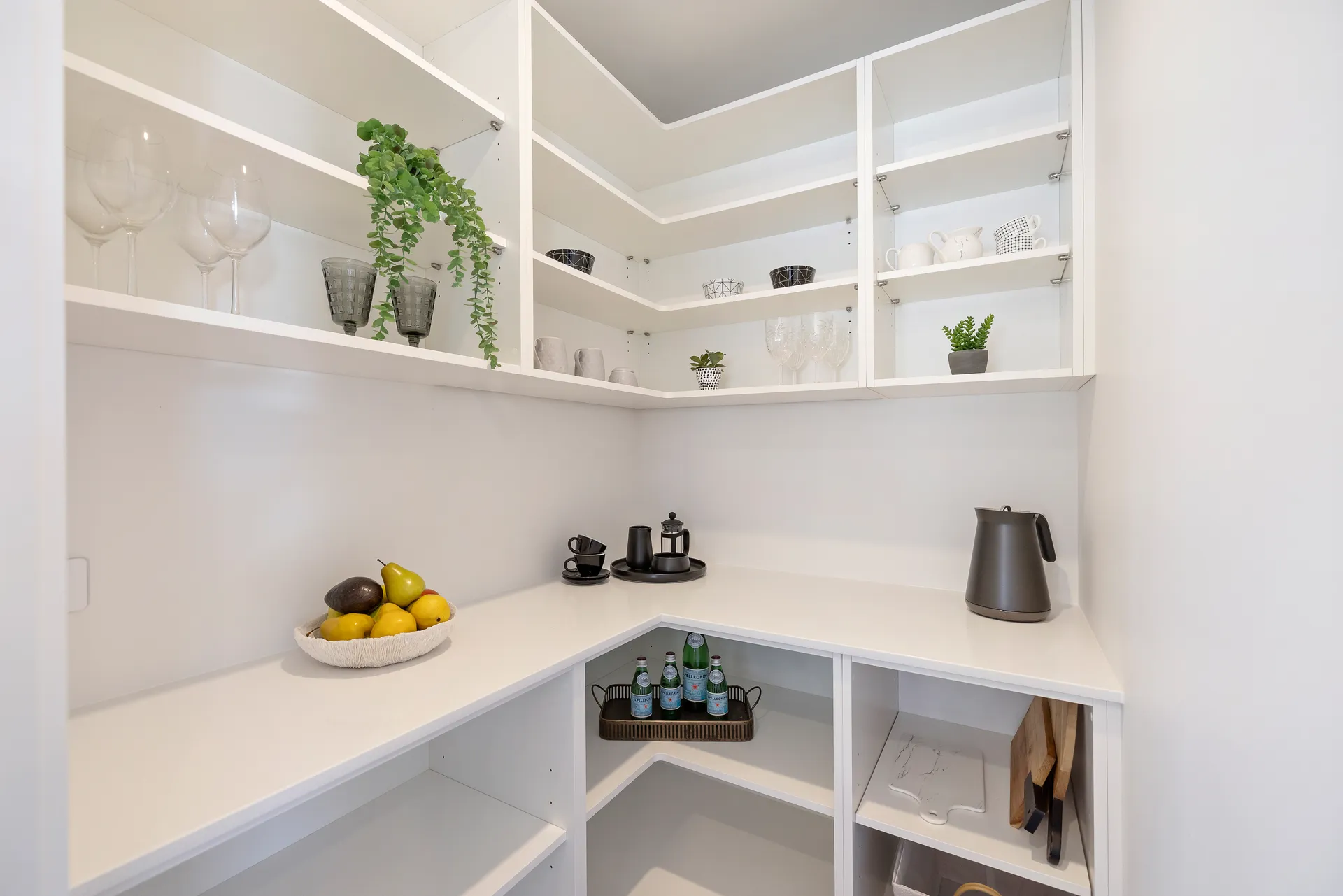 White scullery with open corner shelving above a bench