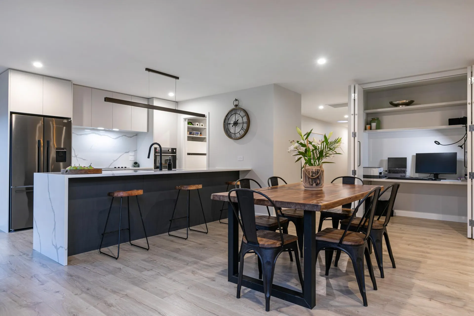 Dark island with bar stools and white cabinetry beside the dining table