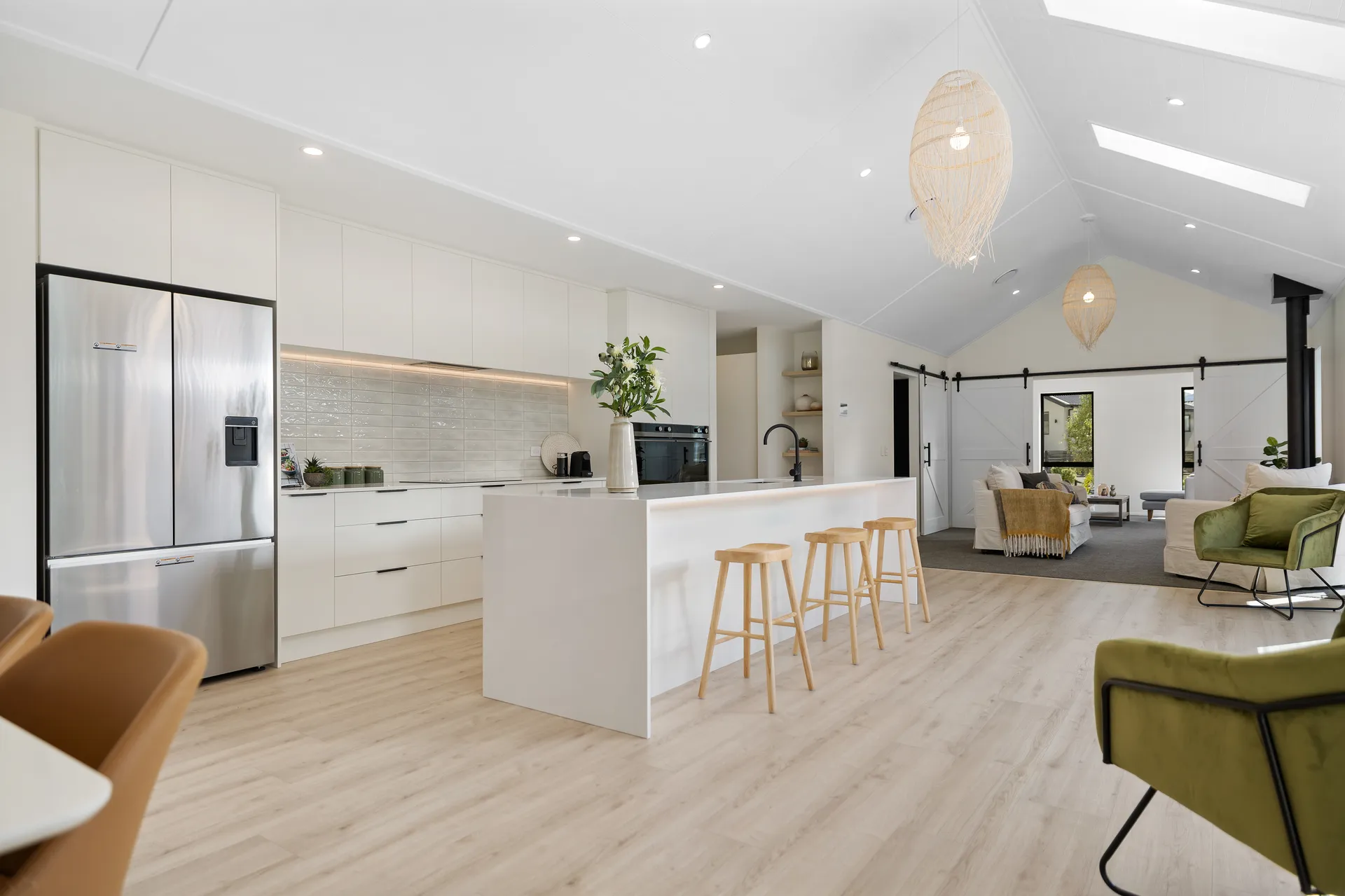 White kitchen and island under a vaulted ceiling with woven pendant lights