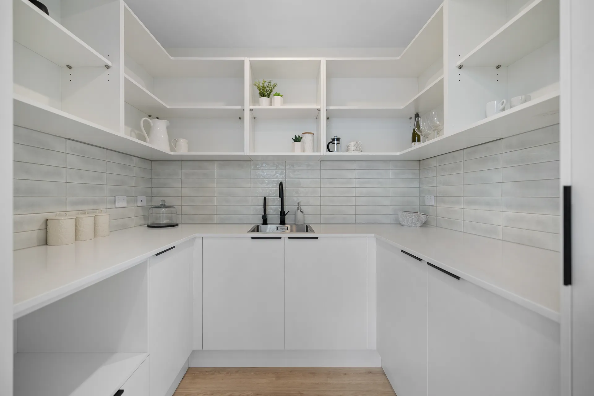 White U-shaped scullery with open shelves and a tiled splashback