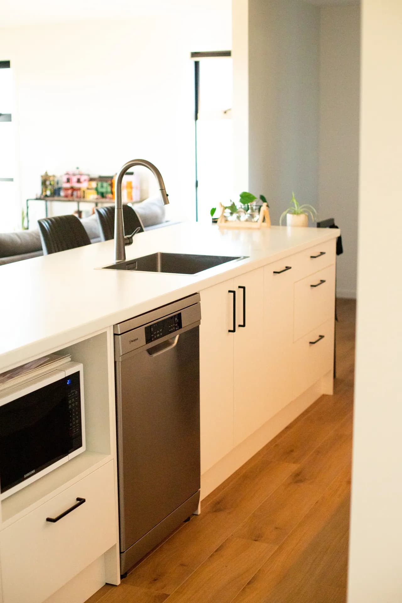 White sink run with black handles, a dishwasher and a microwave nook