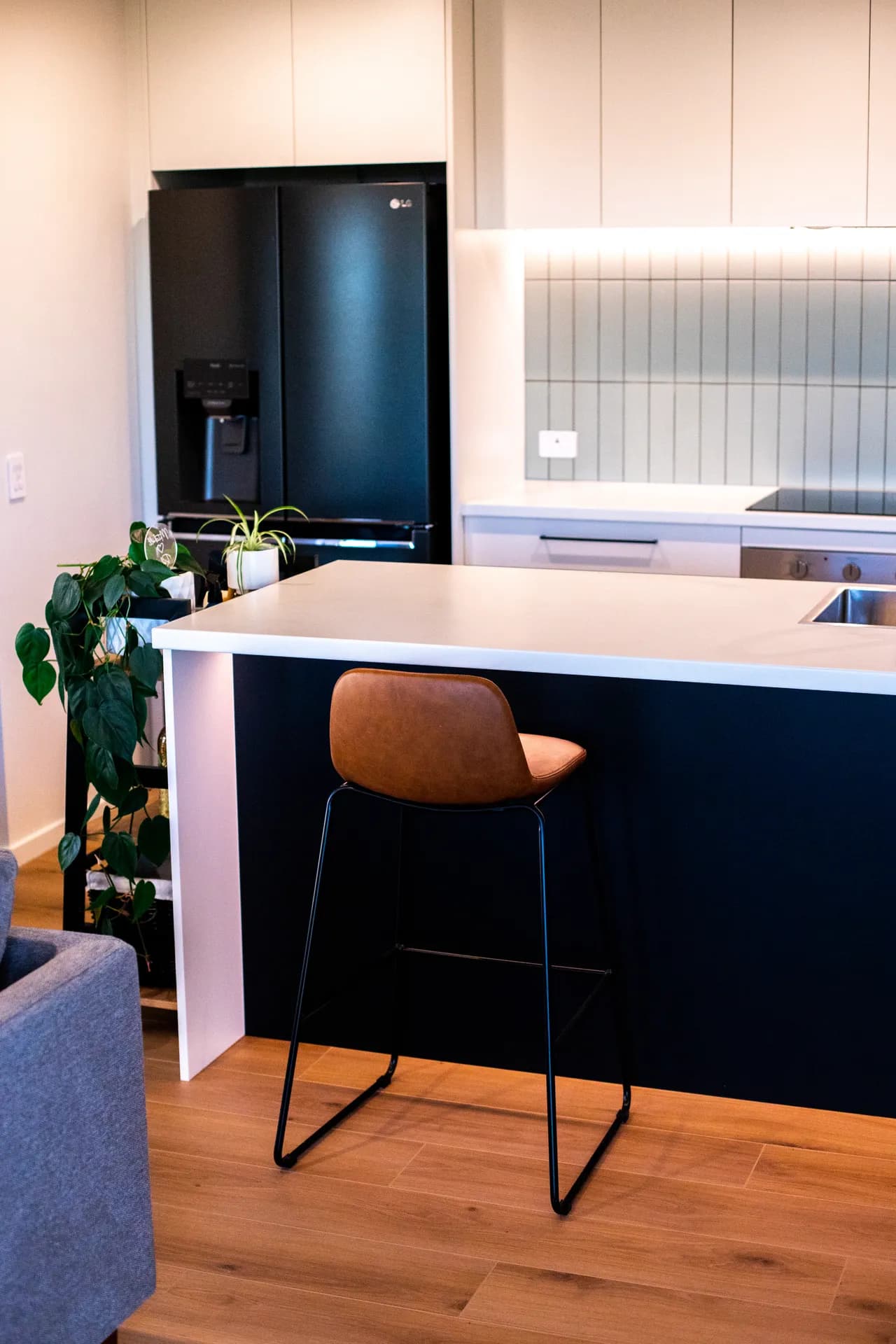 Navy island end with a stool beside a black fridge