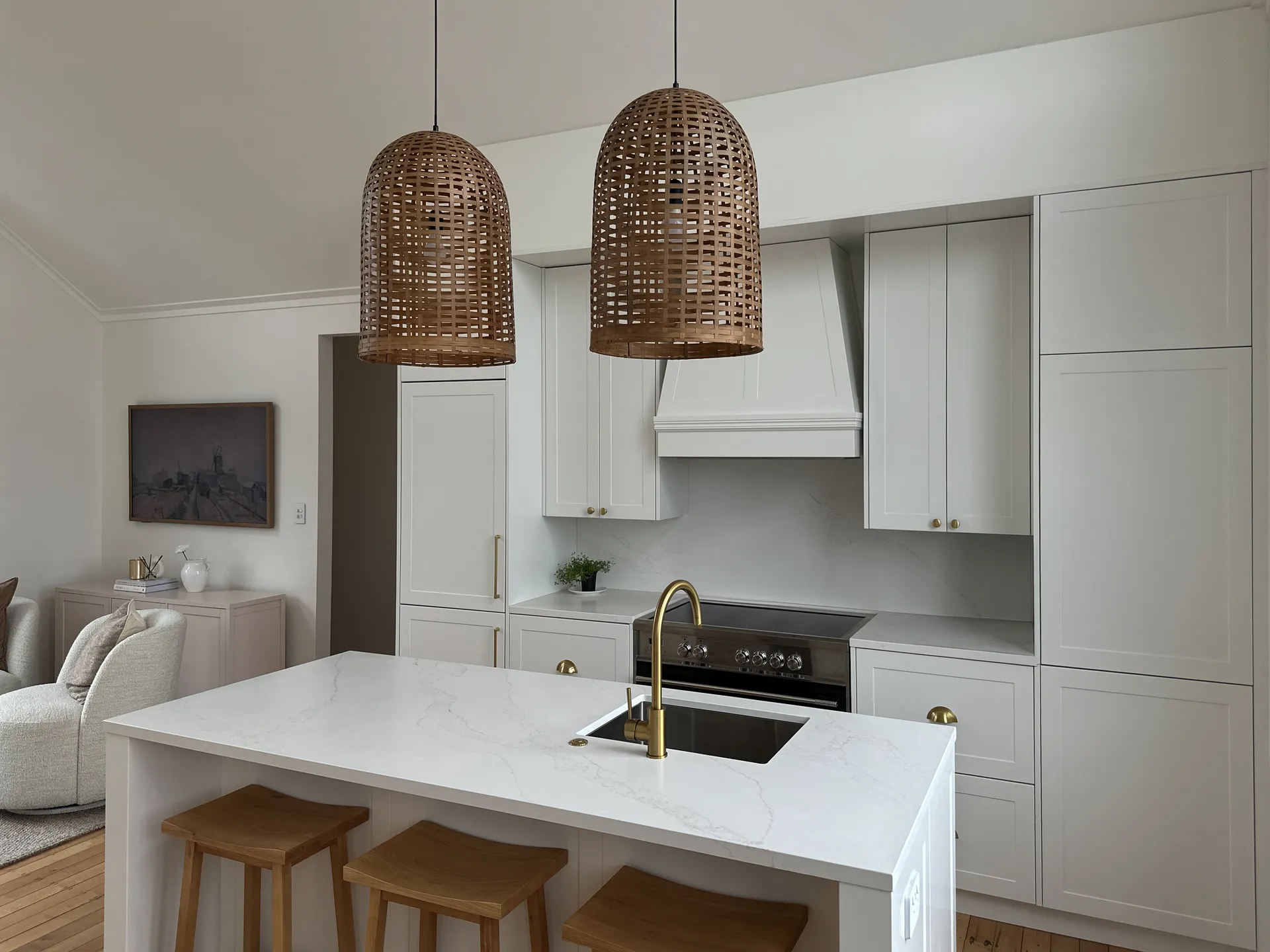 White shaker island and tall cabinets with a canopy rangehood and woven pendant lights