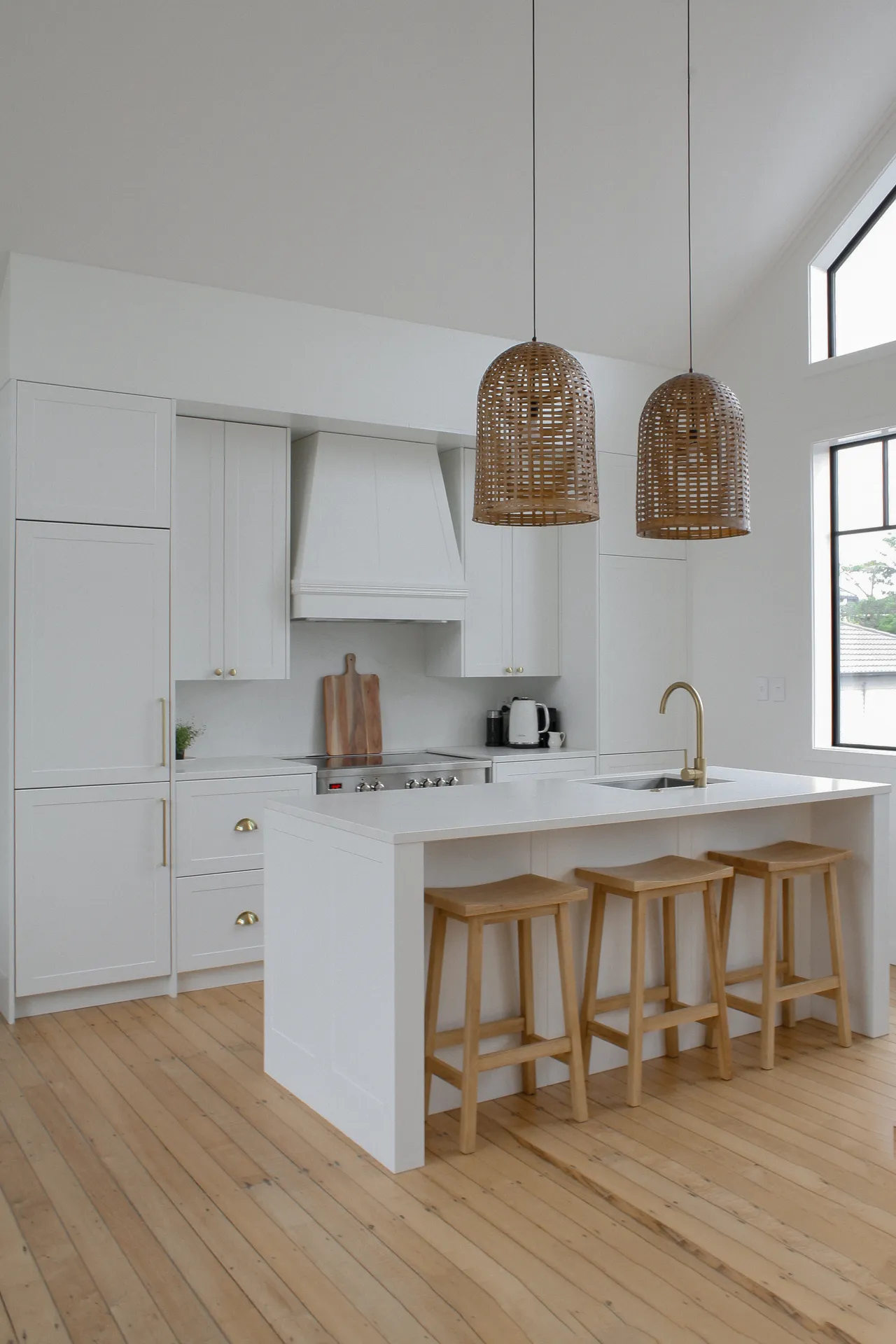Portrait view of a white shaker kitchen and island under a raked ceiling