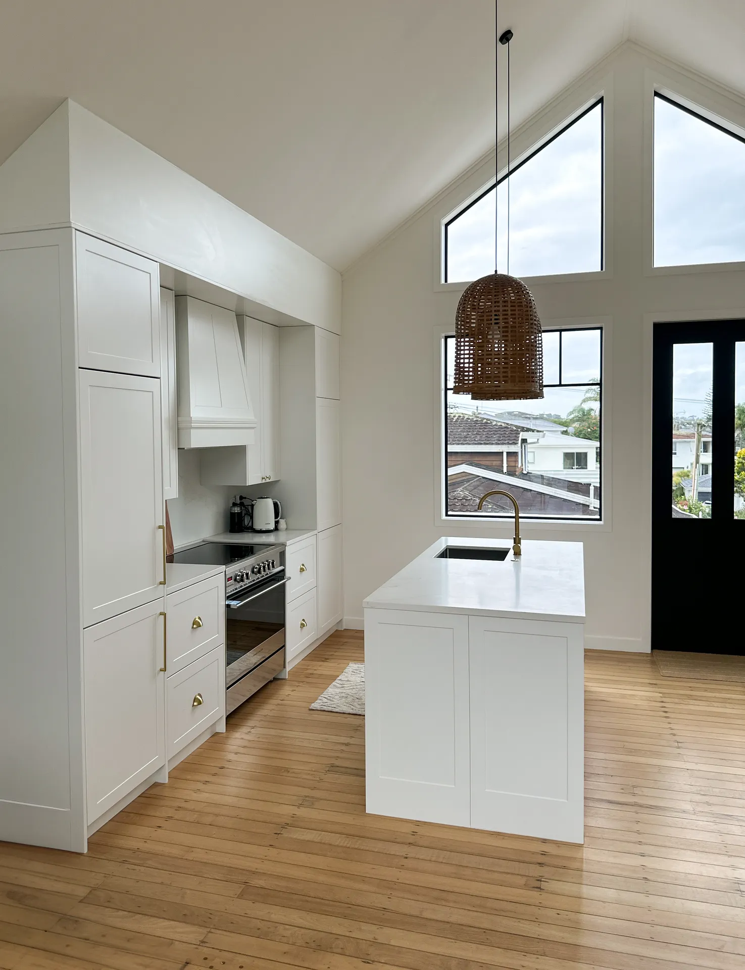Side view along white shaker cabinets to the island and gable windows