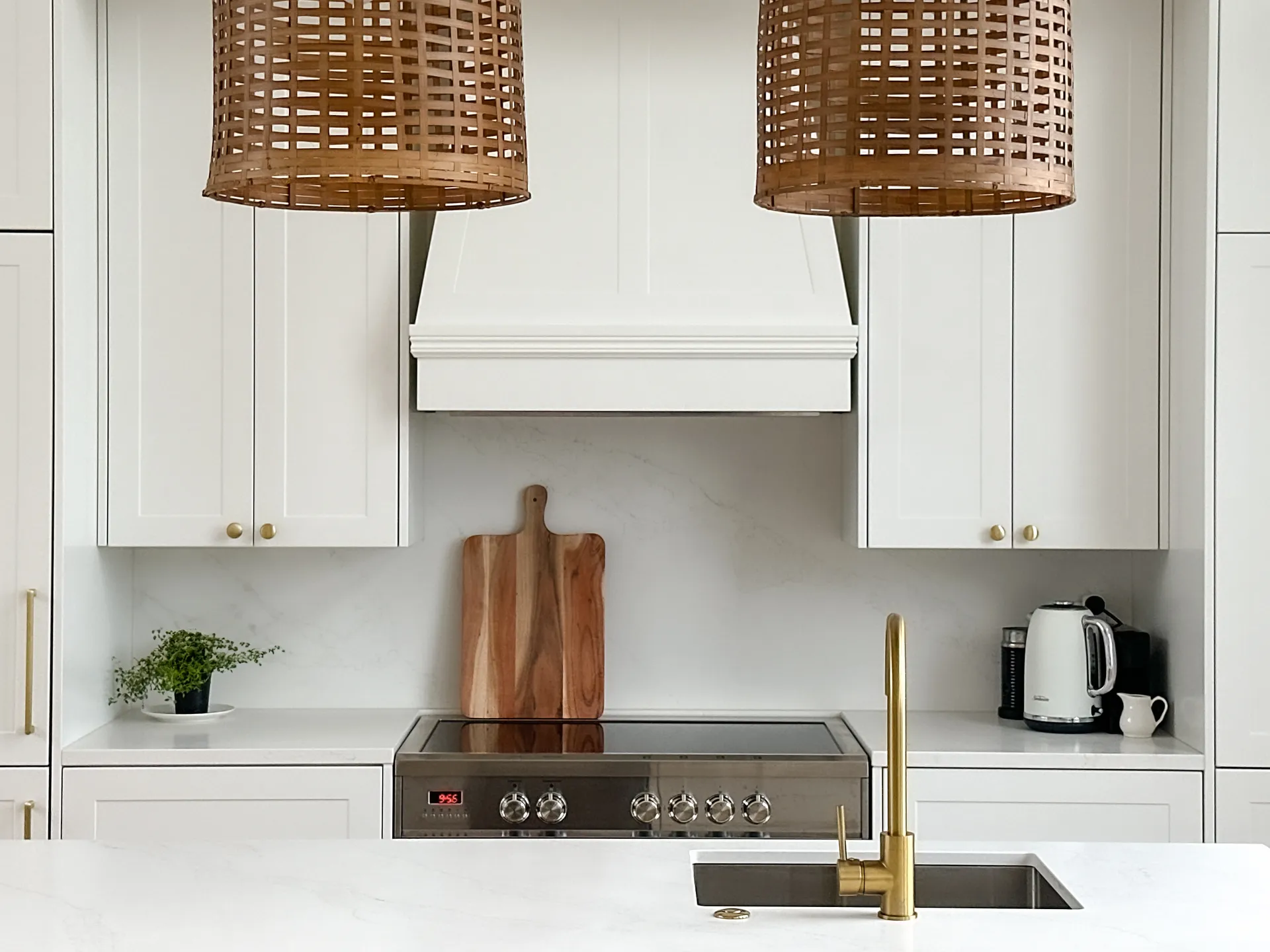 White shaker cooker wall with a canopy rangehood and gold-look tap