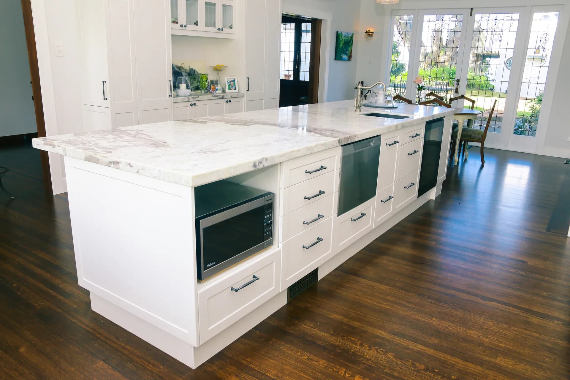 Long white shaker island with microwave and dishwasher bays on a dark floor