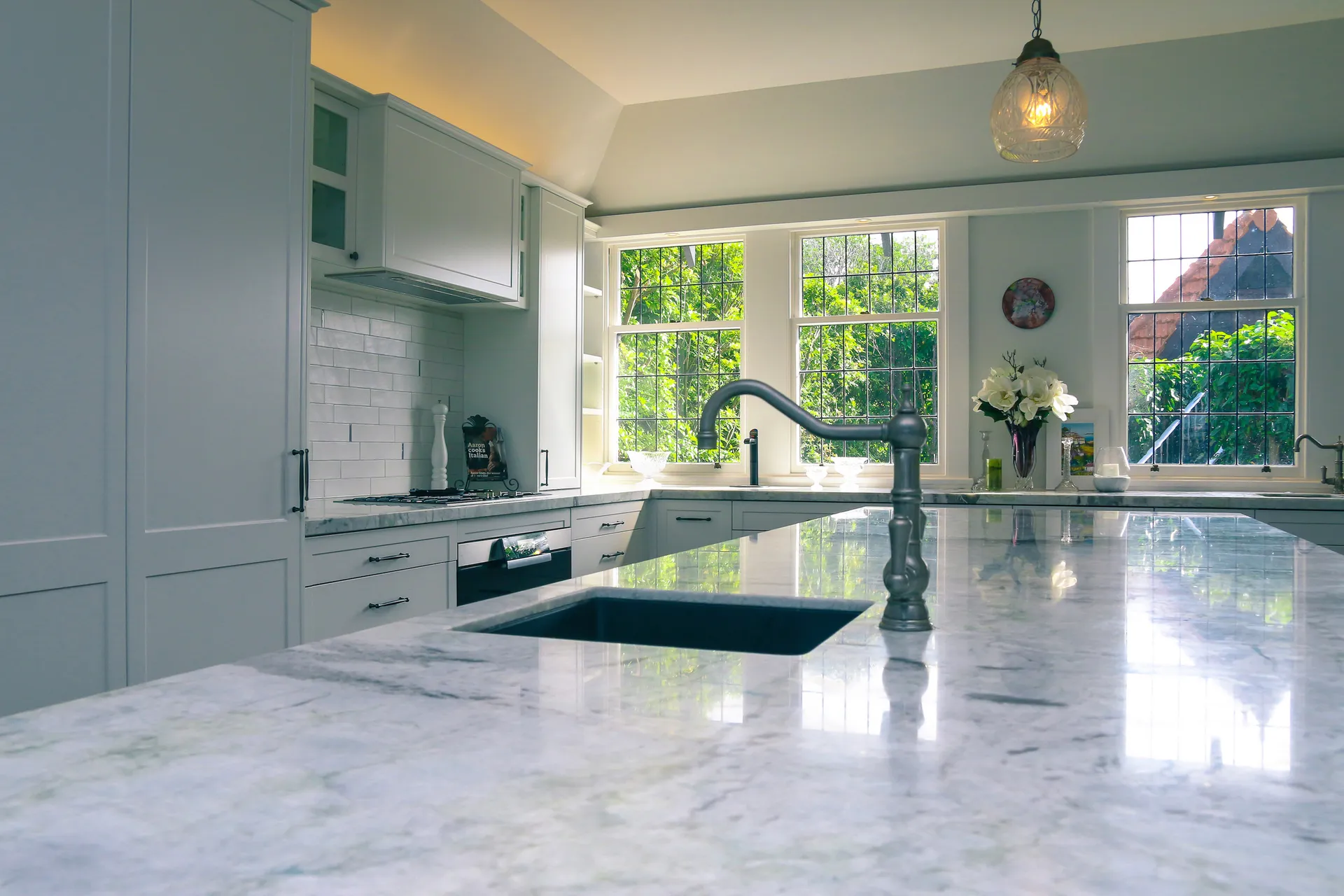 View across the island benchtop to the cooktop wall and leadlight windows