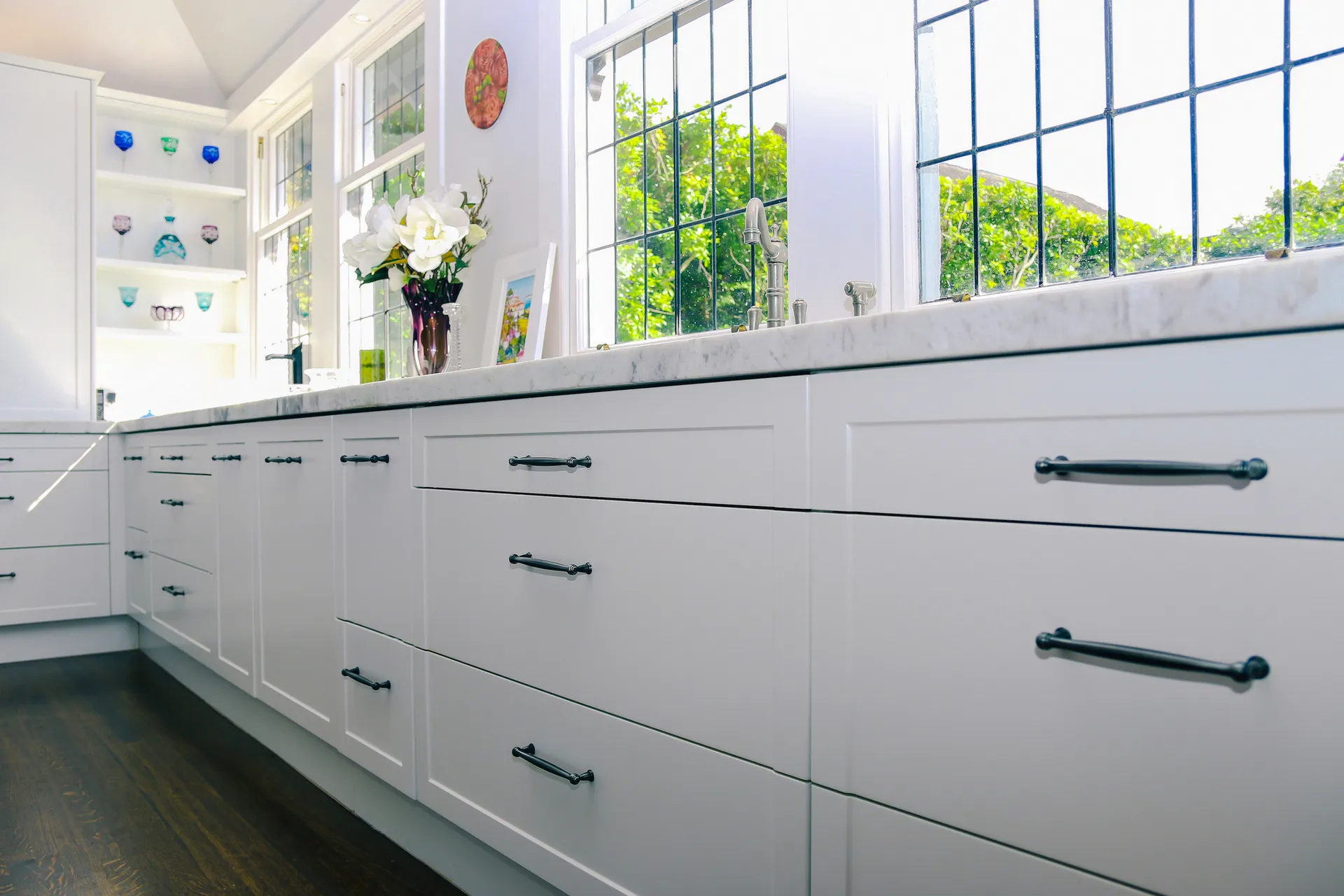 Low view along white shaker drawers with dark handles