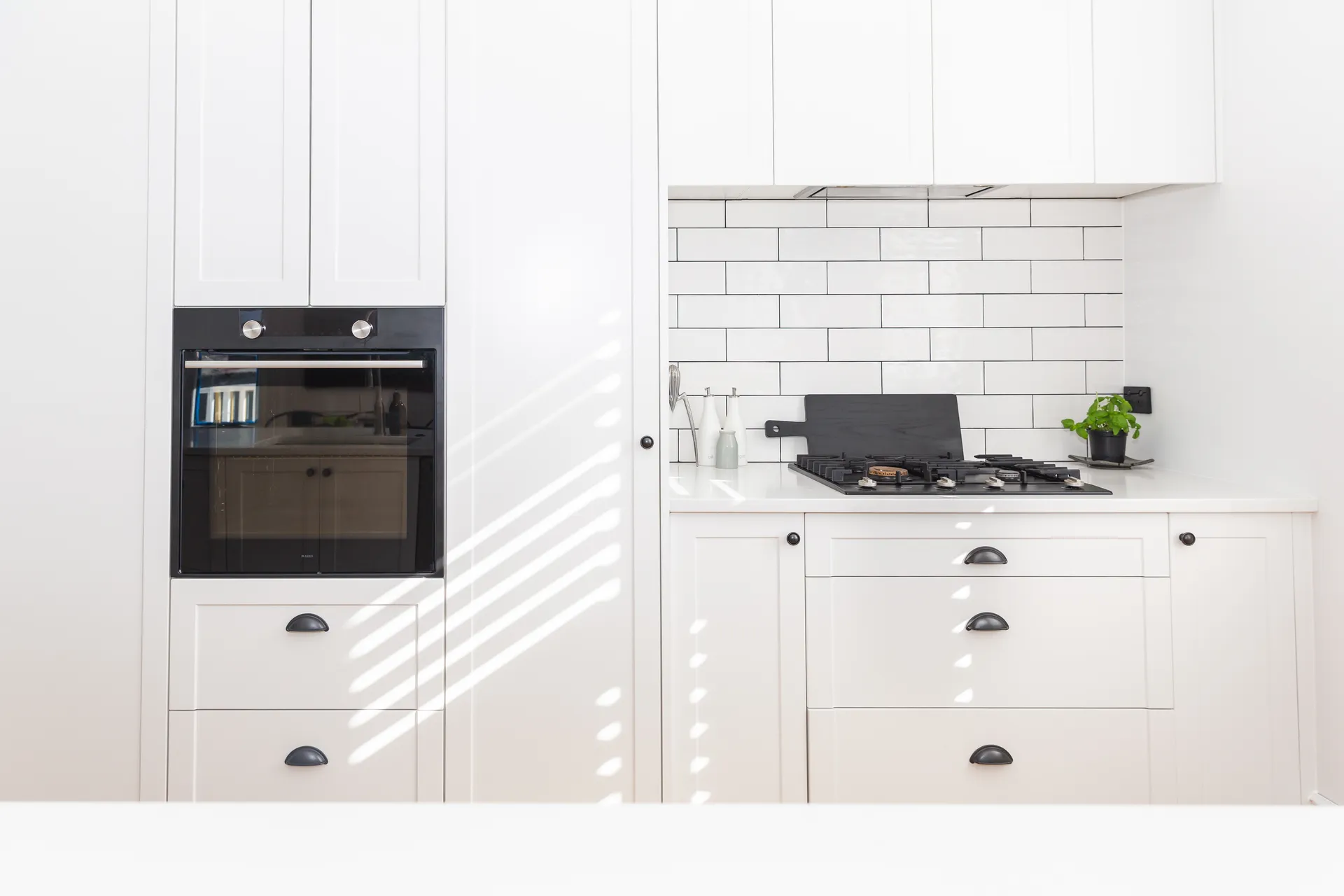 White shaker oven tower and cooktop wall with a subway tile splashback