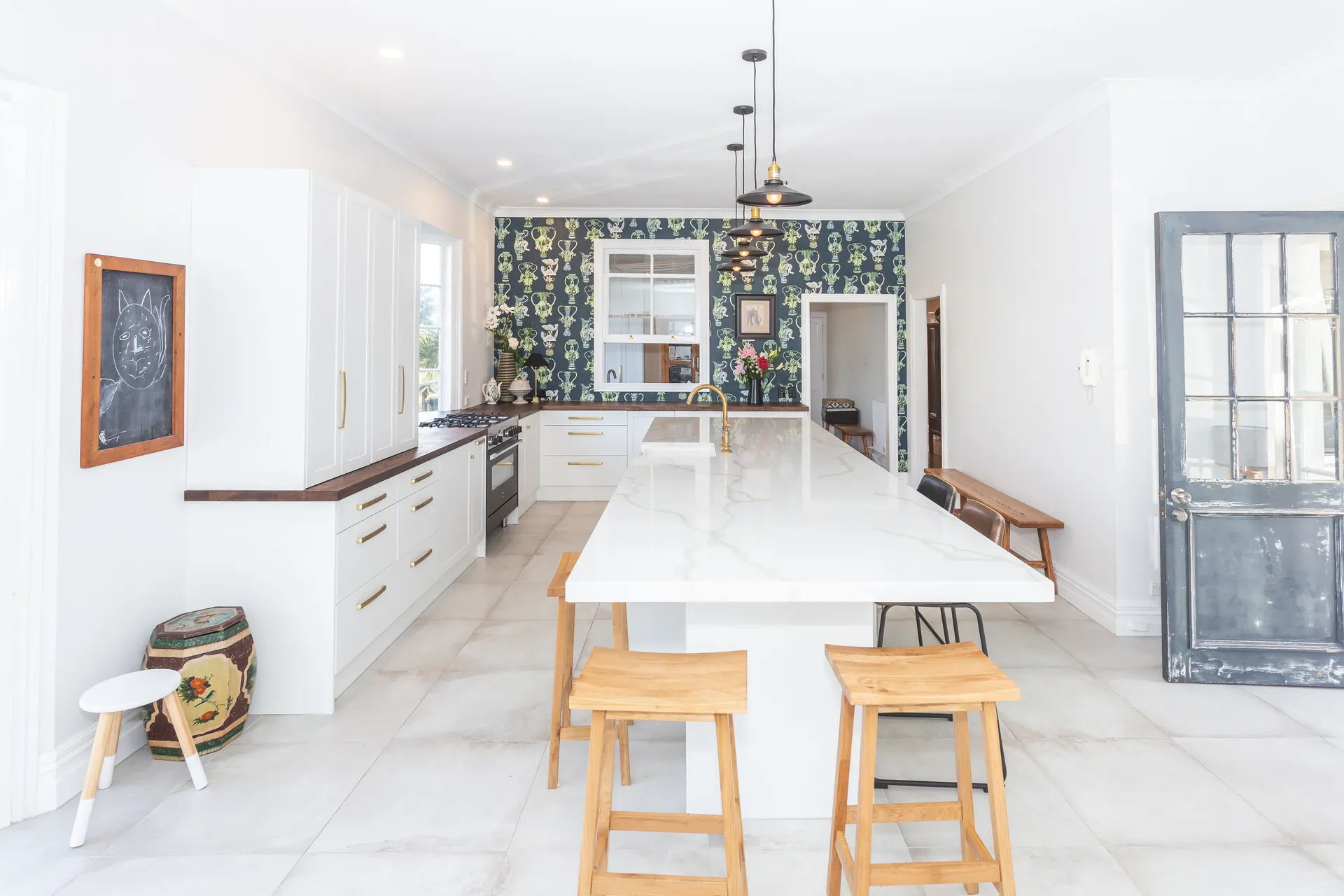 Long white shaker island down the room to patterned wallpaper