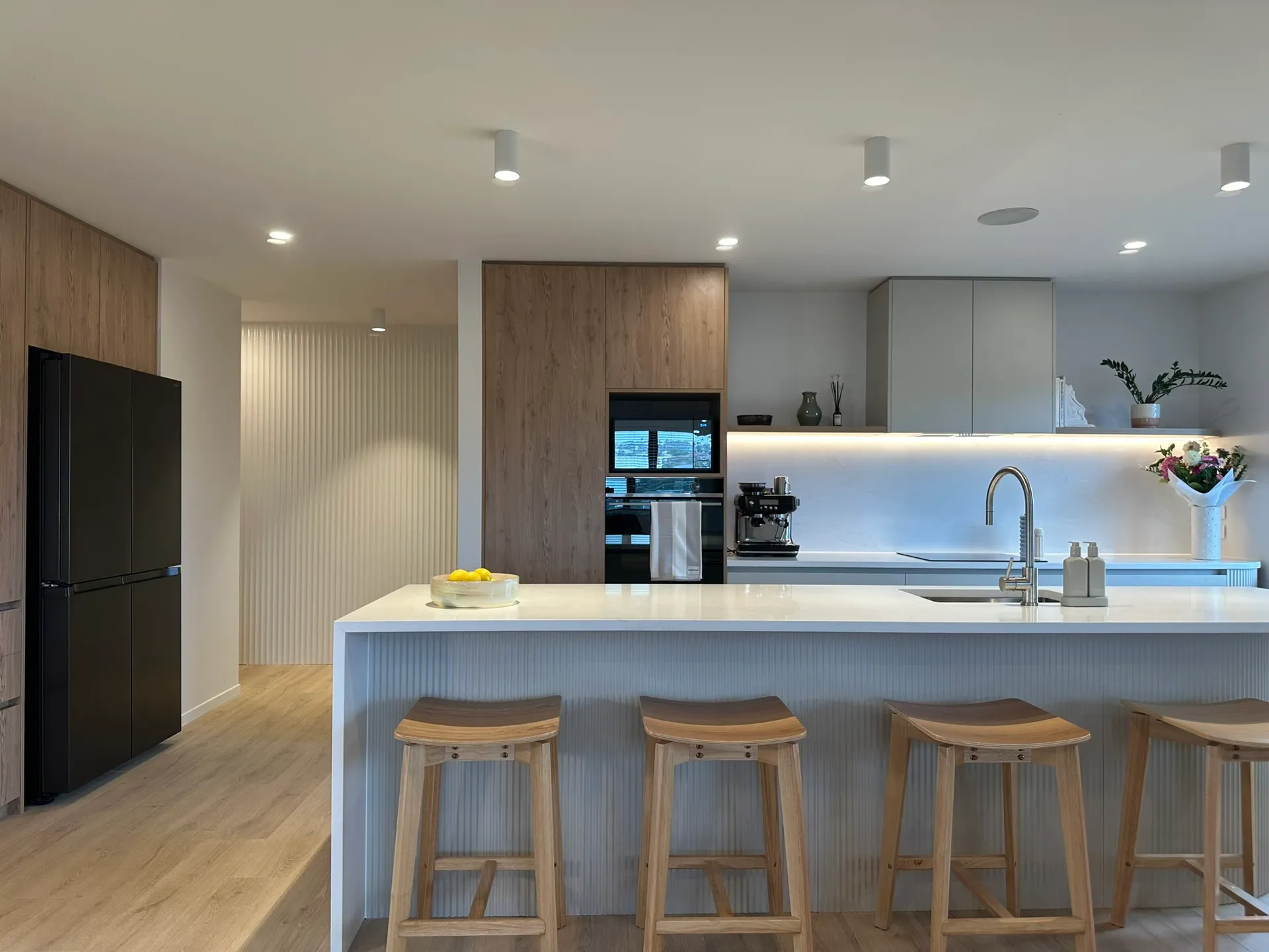 Front-on view of the fluted island and timber-look tall cabinets