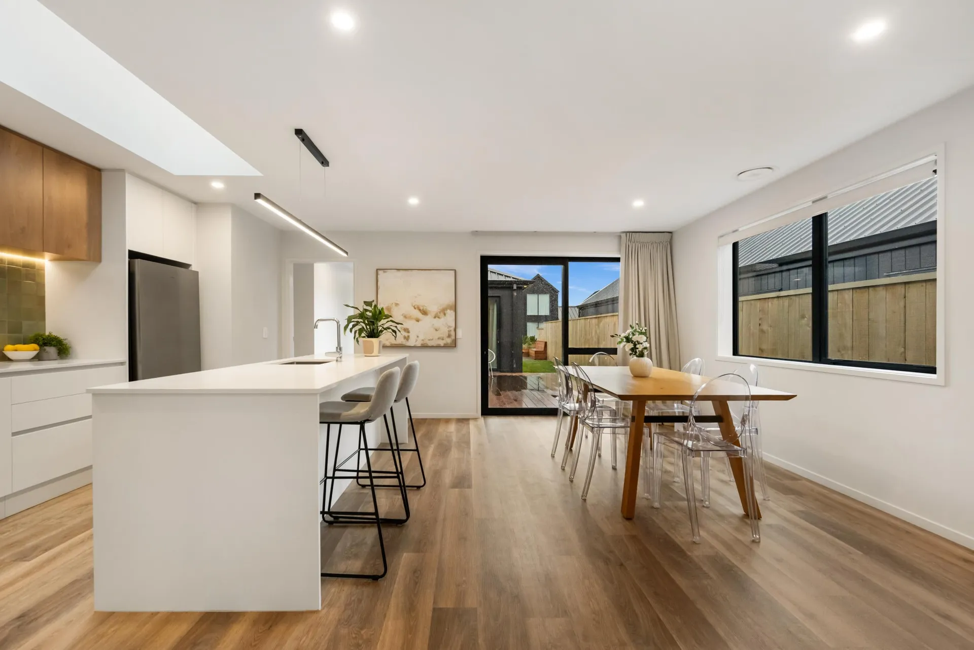 Long white island and timber-look overheads looking through to the dining area
