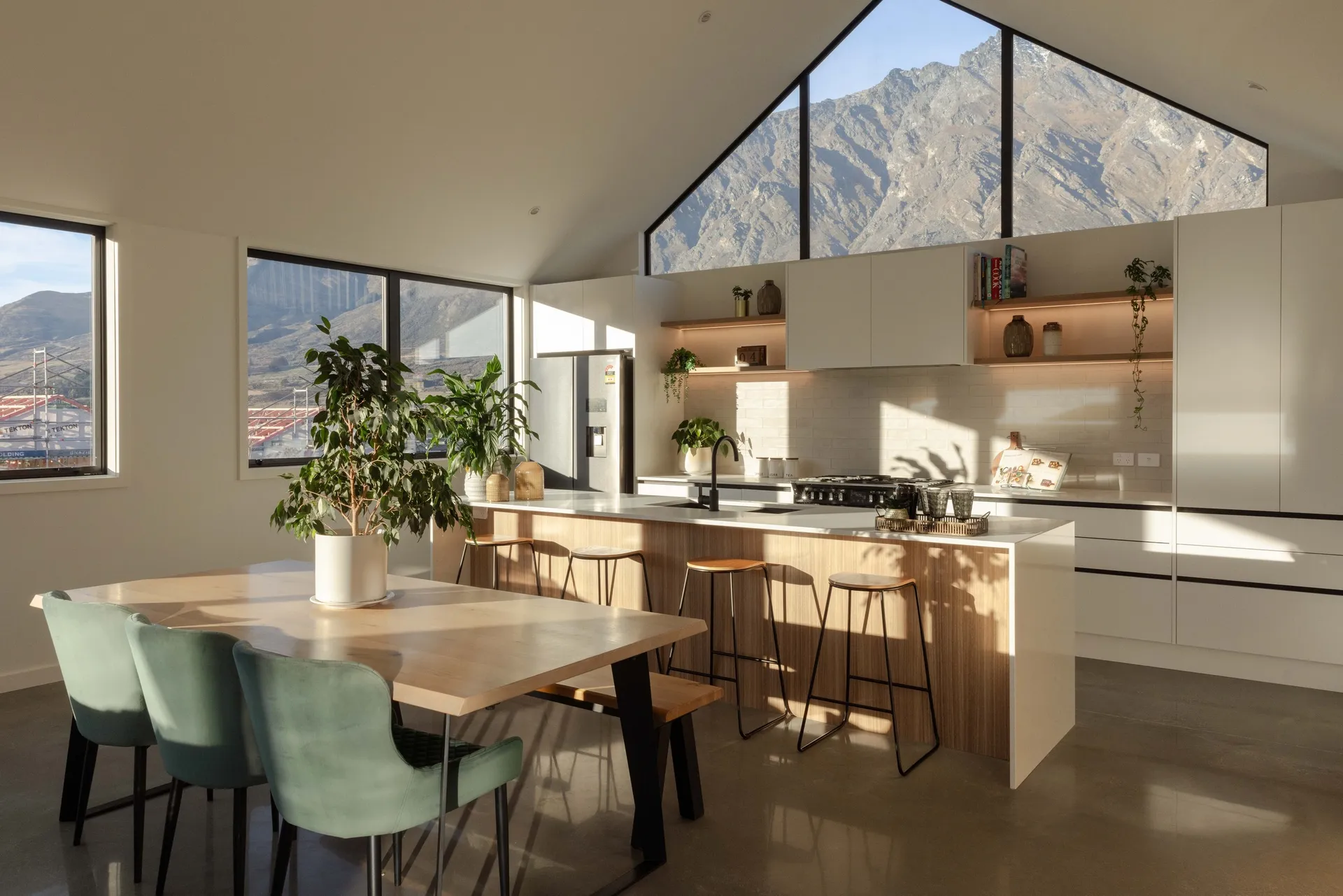 Island with stools and white cabinetry beyond the dining table, mountains through the window