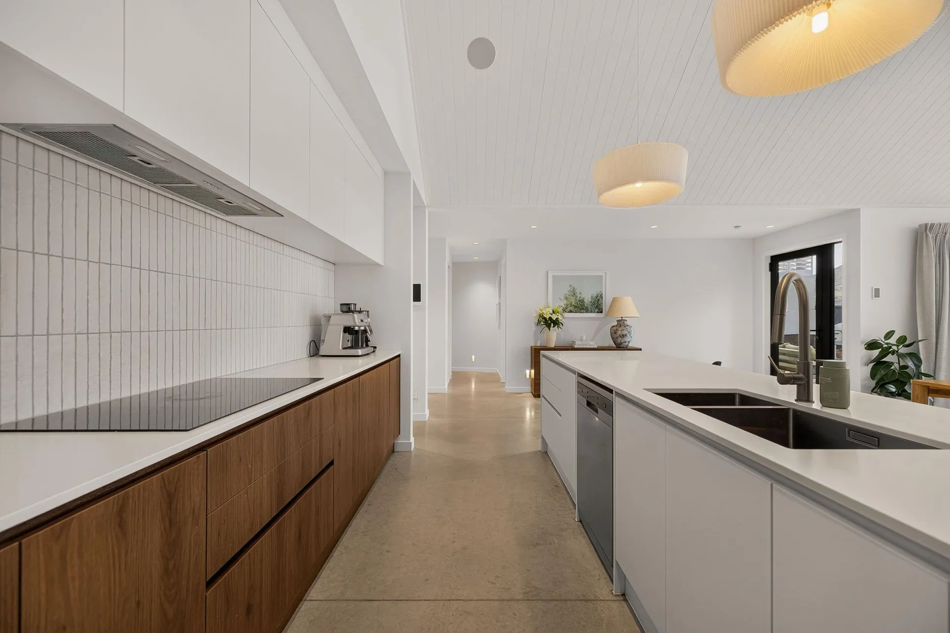 Timber-look drawers with handleless channels opposite the white island sink run