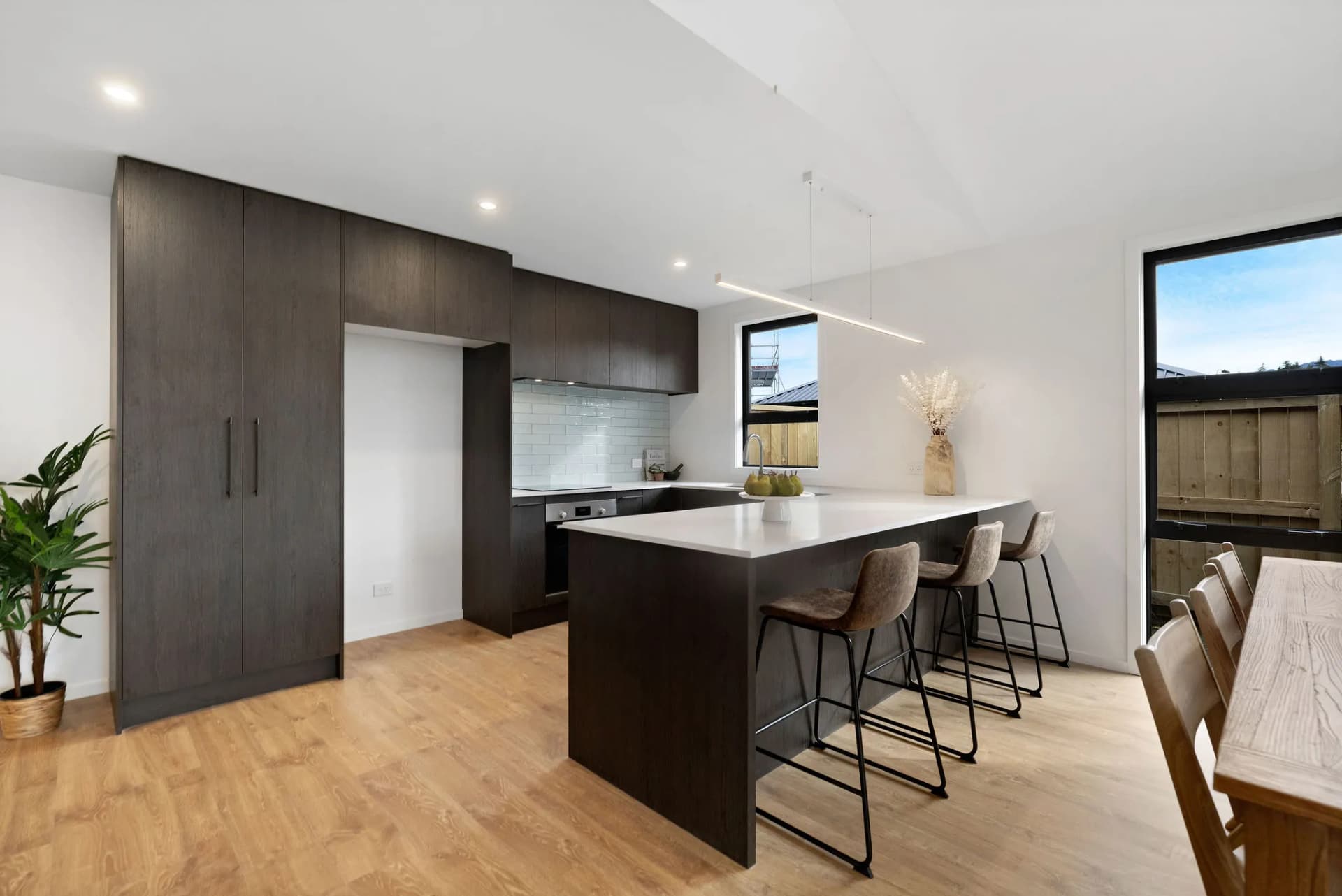 Tall dark timber-look cabinets and a peninsula with bar stools