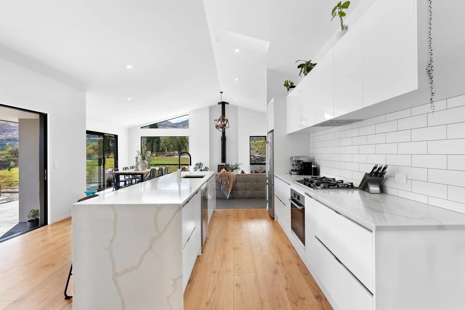 White galley with a marble-look waterfall island and a white tiled splashback