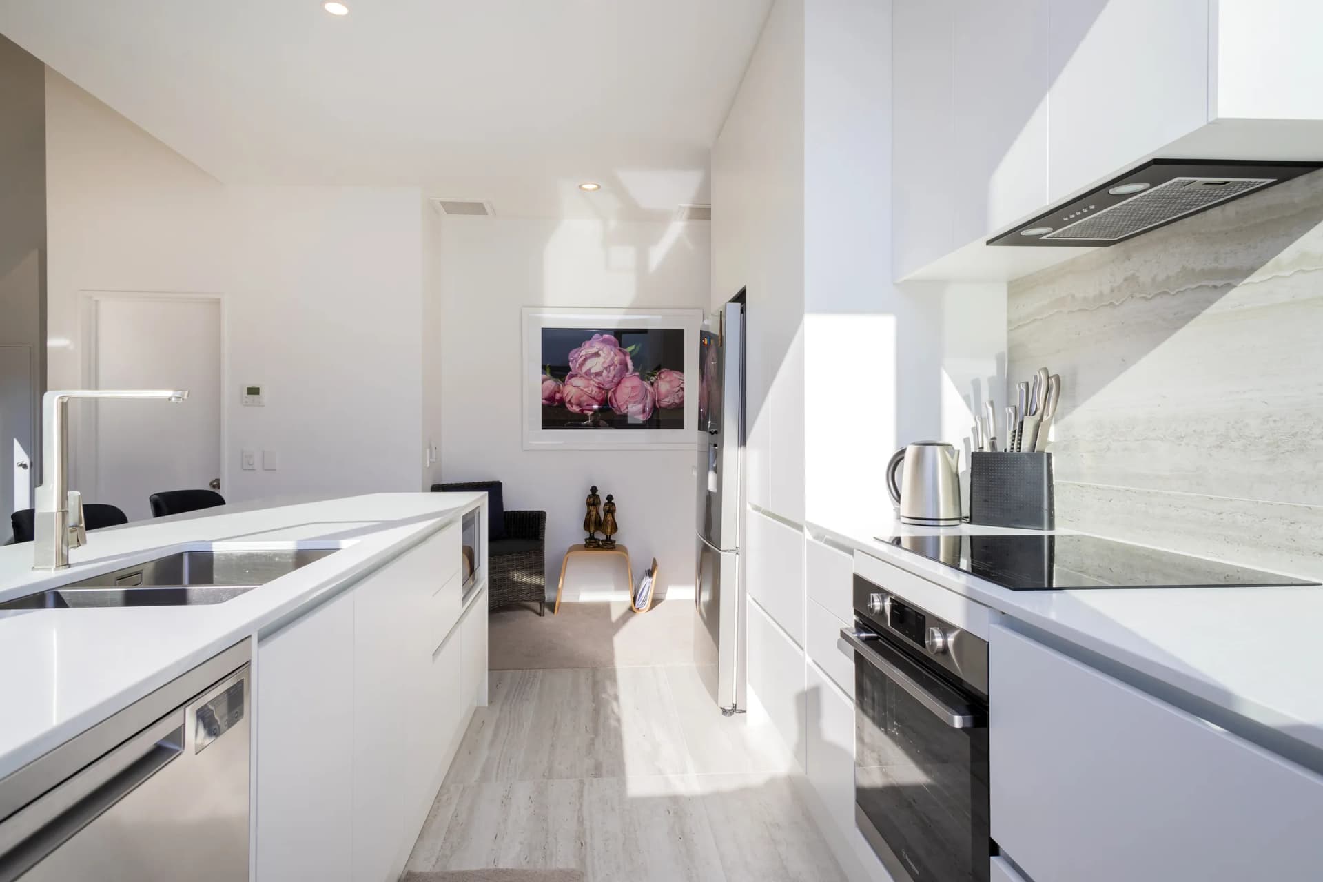 White handleless galley between the island and the cooktop run