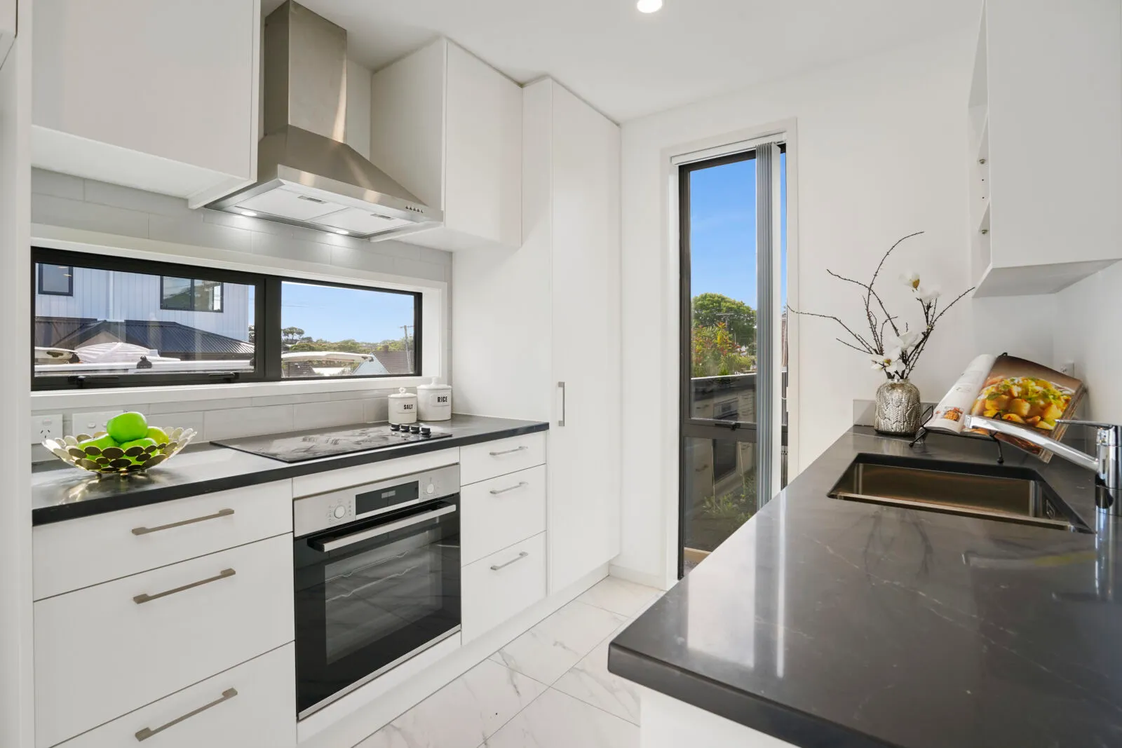 White cabinets with bar handles, a dark benchtop and a window splashback