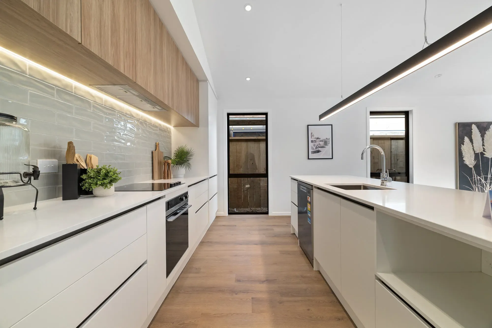White galley with timber-look overheads and LED strip lighting above a tiled splashback