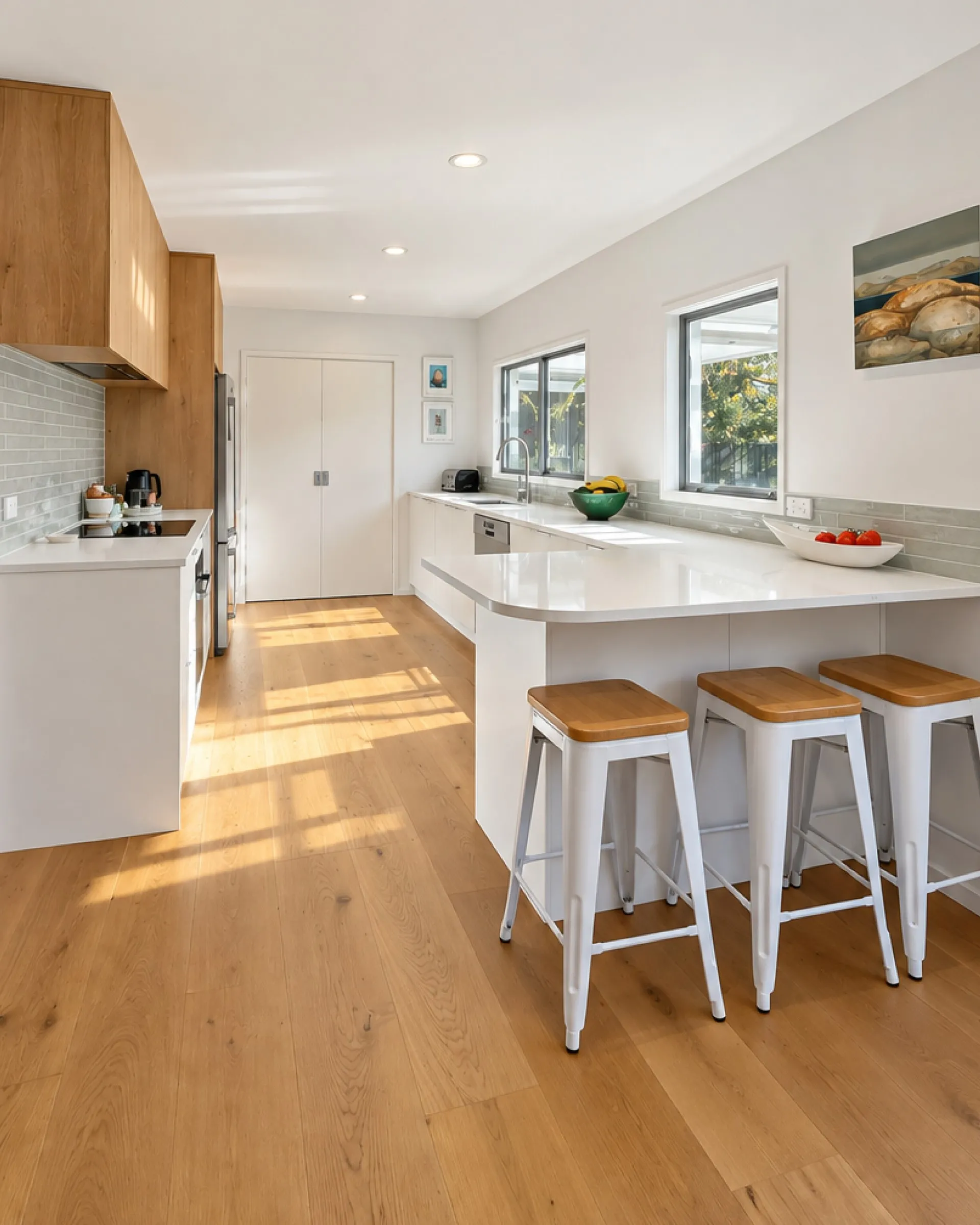 White kitchen with a curved peninsula, white stools and timber-look overheads