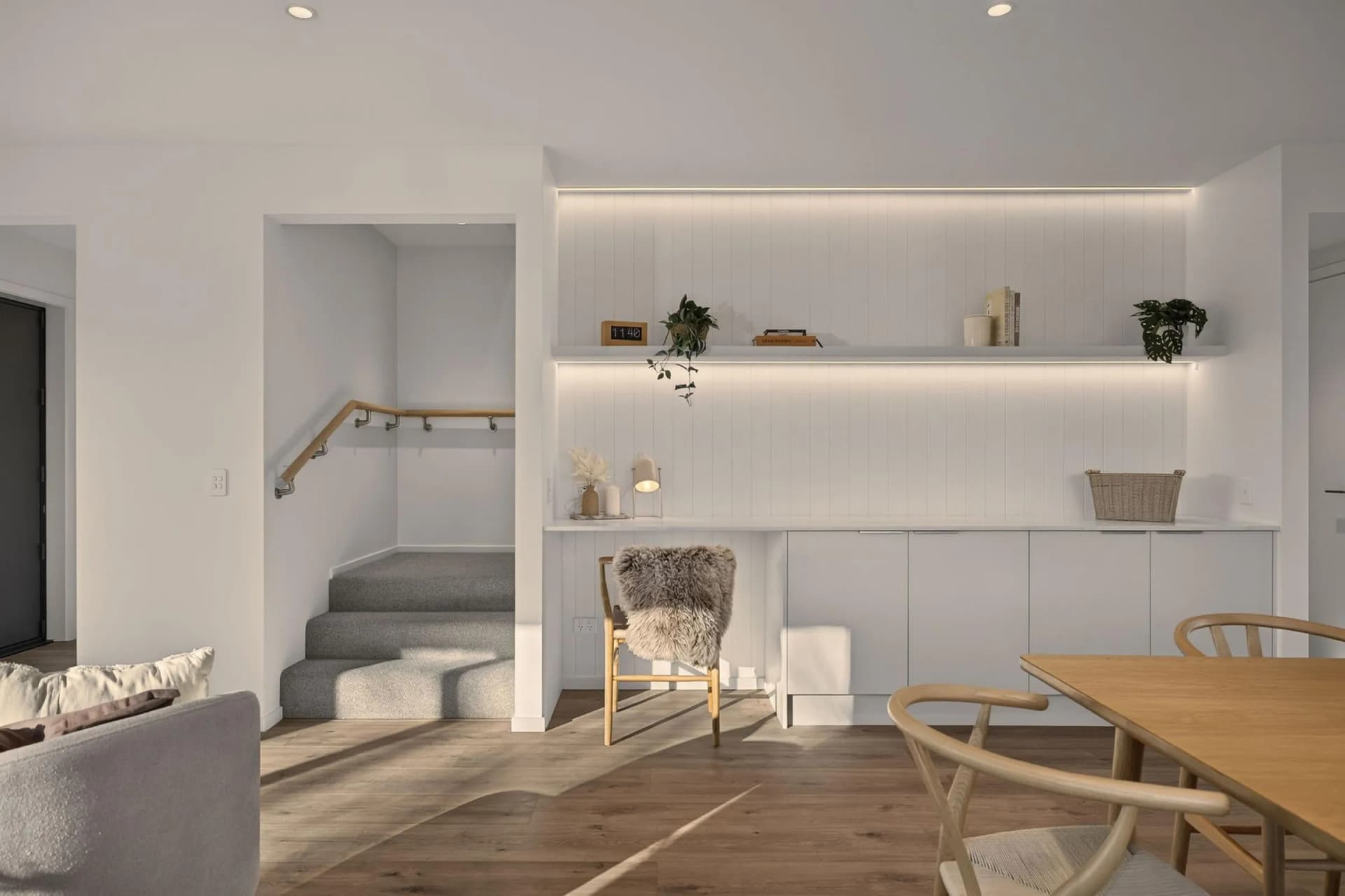 Full-height white panelled wall with lit floating shelves above handleless base cupboards