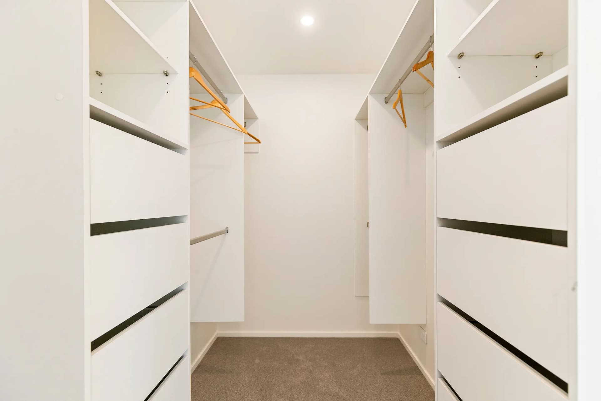 Symmetrical white walk-in wardrobe with drawer banks and hanging rails